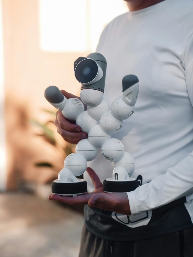 A person in white long sleeves holding a futuristic humanoid robot indoors.